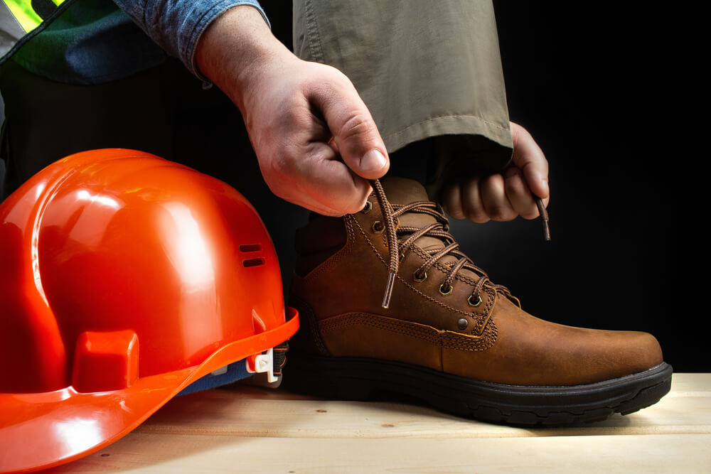 Worker with helmet lacing up leather boots